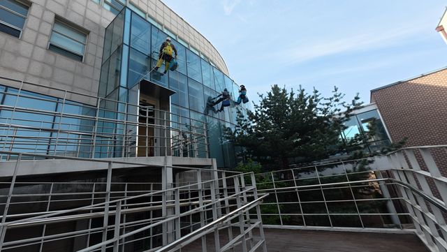 로프 작업으로 청소 중인 고층 건물 유리 외벽